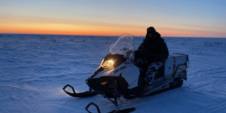 mark on a snowmobile with the Alaskan sunrise behind him