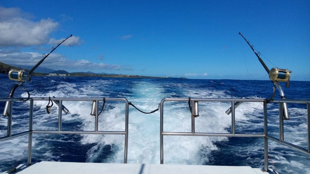 Fishing boat waves on ocean, distant shoreline view.