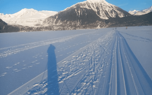 Snowy mountain landscape with ski tracks and shadows.