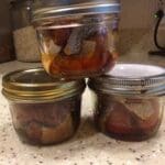 Three jars of preserved salmon on counter.