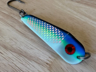 Colorful fishing lure with red eye on wooden surface