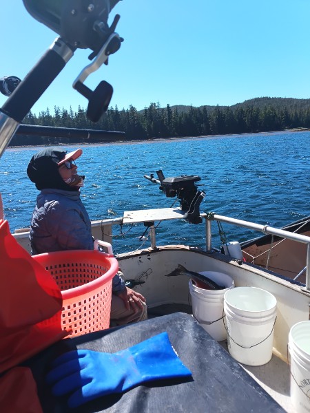 Person on fishing boat with buckets on calm blue lake